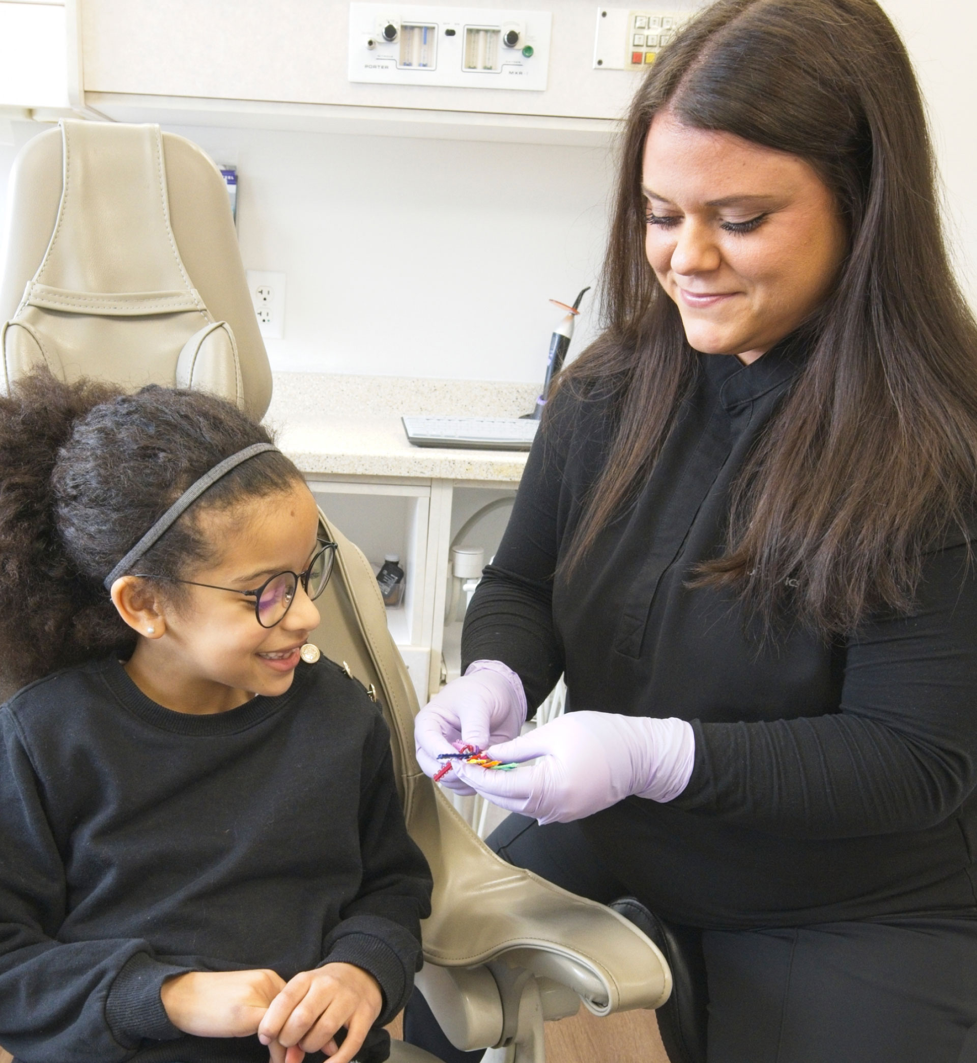 dental assistant showing young patient different colors of dental spacers for braces