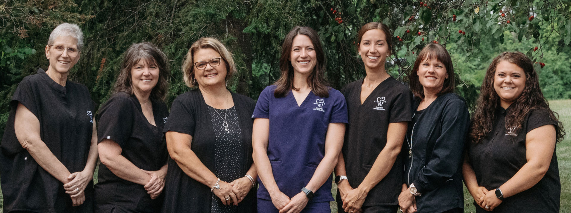 Dr. Dani and team posing for photo in front of line of trees